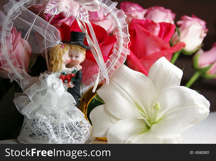 Figurine of bride and groom kissing over roses background. Figurine of bride and groom kissing over roses background