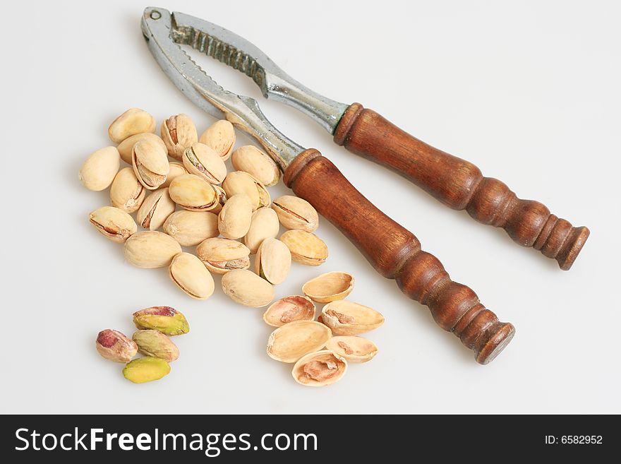 Pistachio nuts with nut cracker isolated in white background