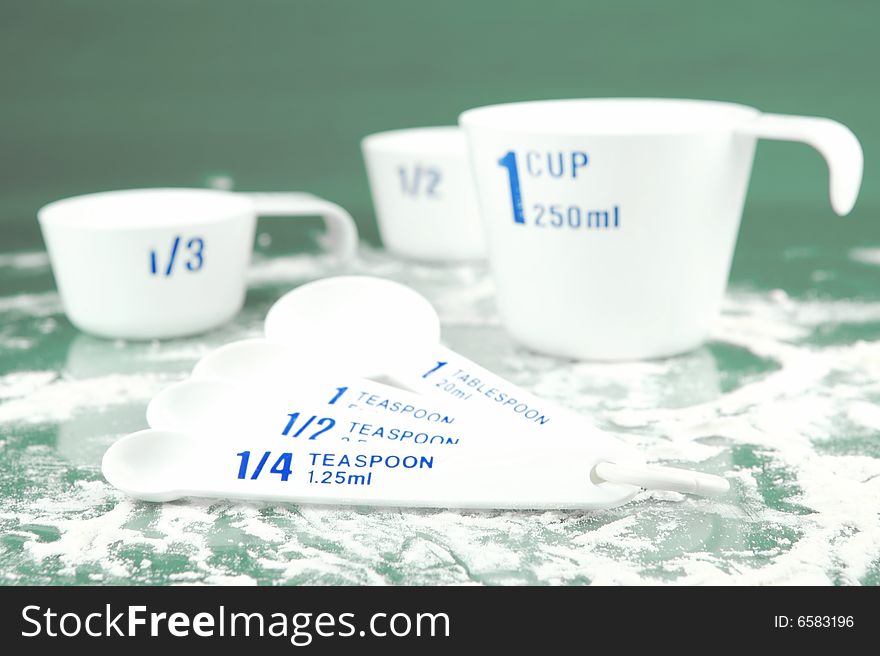 Measuring cups and spoons isolated against a green background. Measuring cups and spoons isolated against a green background