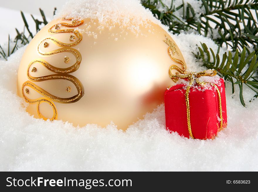 Gold Christmas bauble with present and snow. Gold Christmas bauble with present and snow