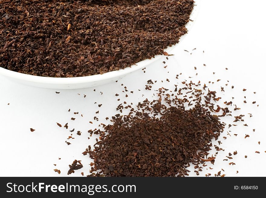 Close up of tea leaves in cup on white background