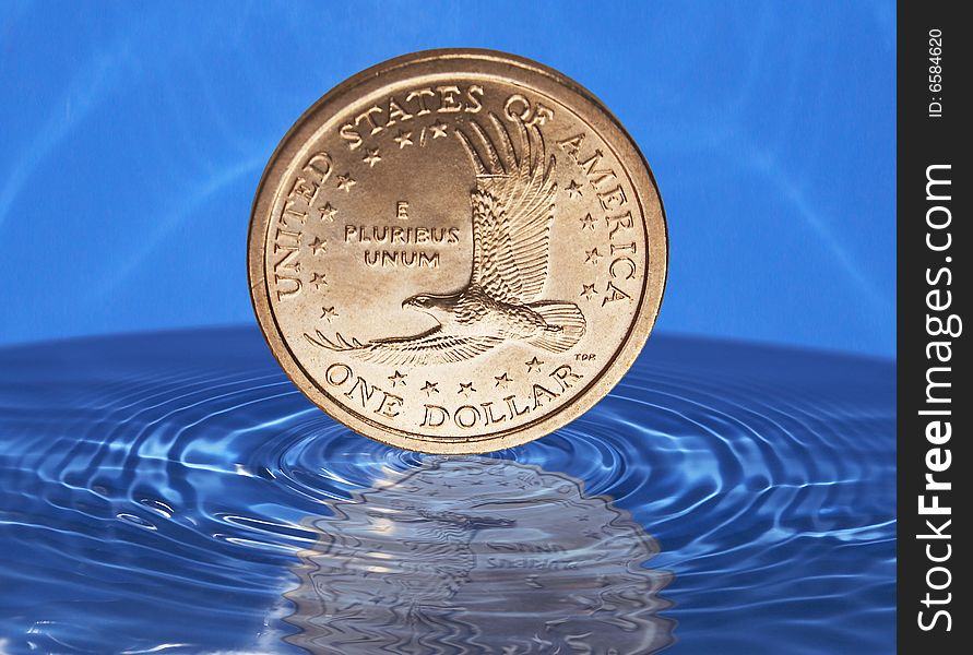 One Dollar coin is falling down in the water. One Dollar coin is falling down in the water