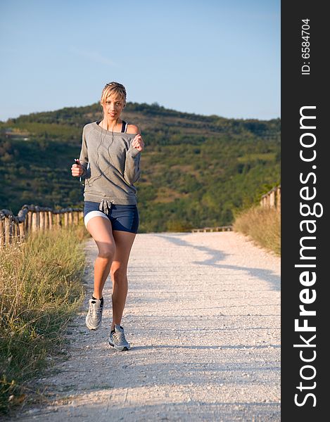 Young woman jogging in a hilly trail at sunset