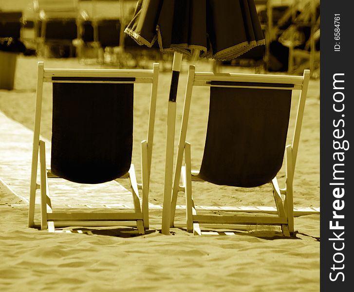 A monochrome of two beach chairs on the sand