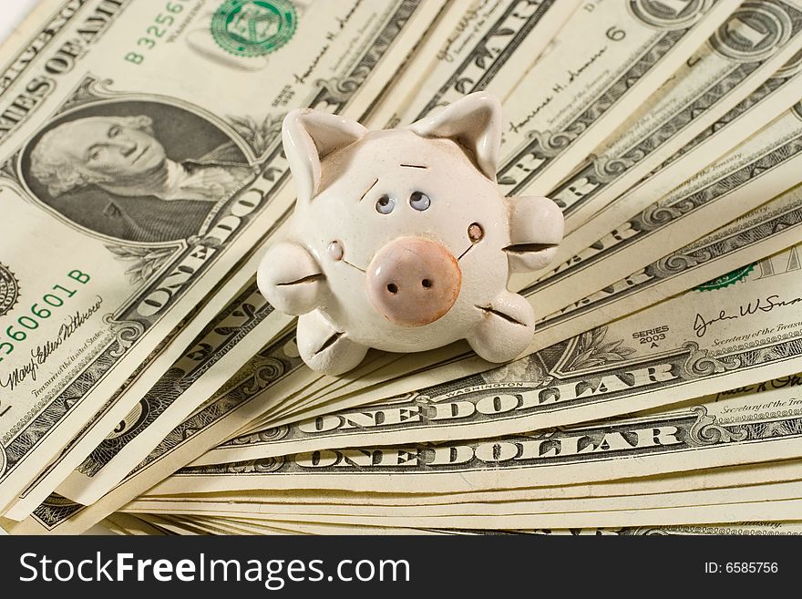 Cute small old ceramic piggy bank on a pile of dollars. Cute small old ceramic piggy bank on a pile of dollars