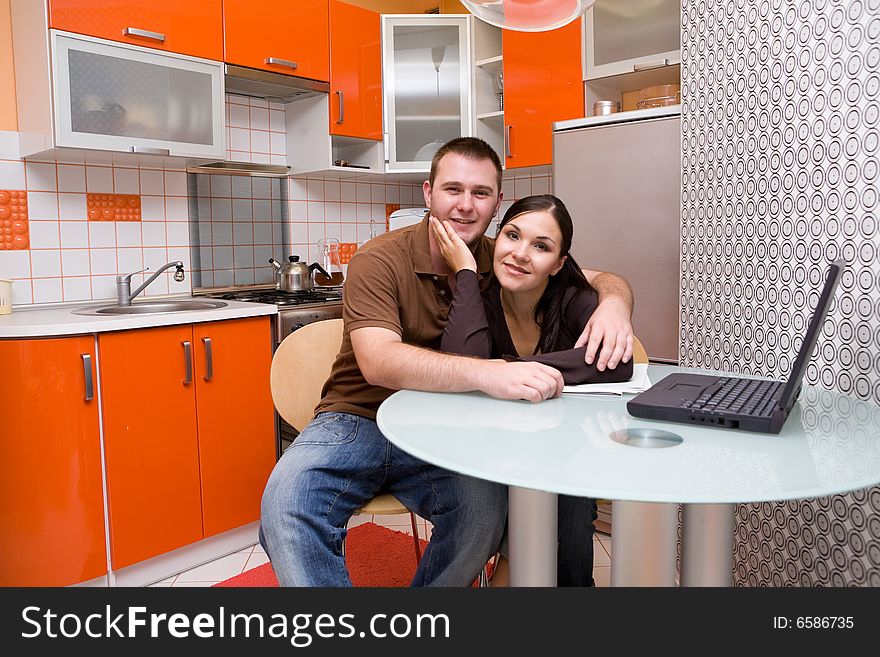 Casual couple with laptop in modern kitchen. Casual couple with laptop in modern kitchen