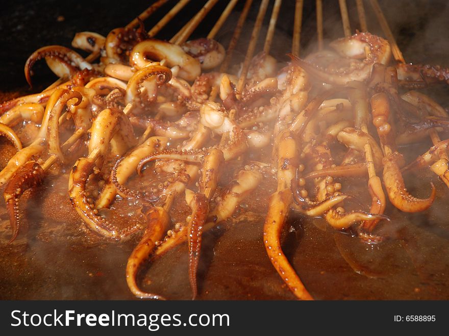 The strings of grilled scented sauced octopuses on bamboo sticker. The strings of grilled scented sauced octopuses on bamboo sticker.