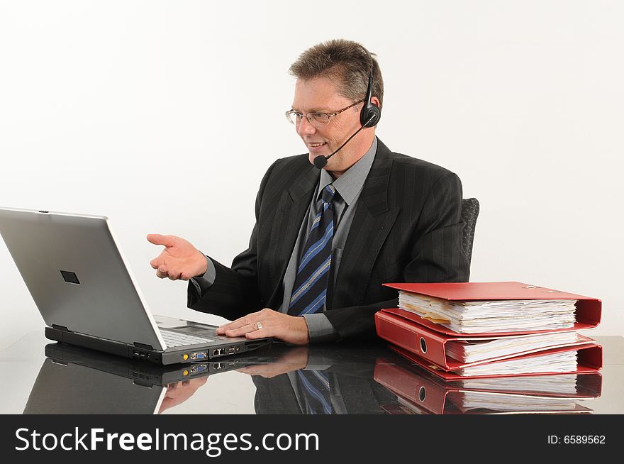 Business man at the office, working with headset and laptop.