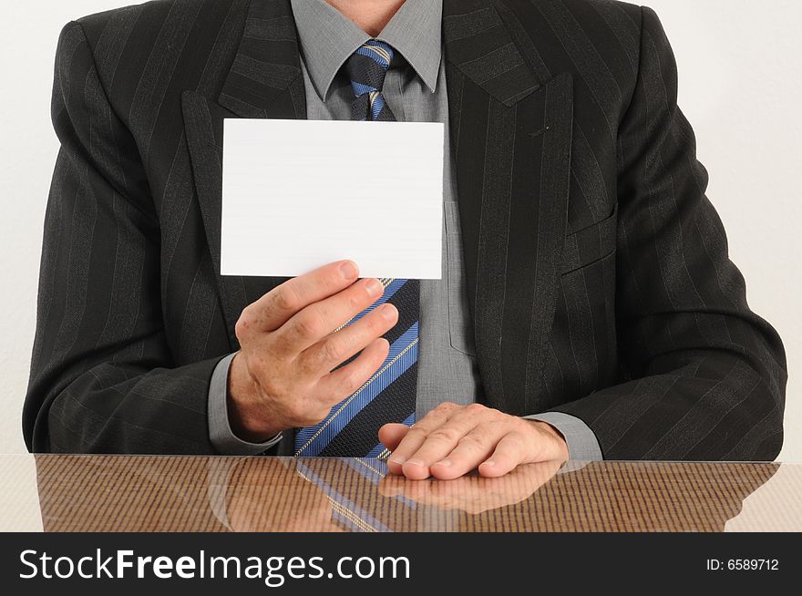 Business man holding a blank card in hand, wearing jacket and tie.