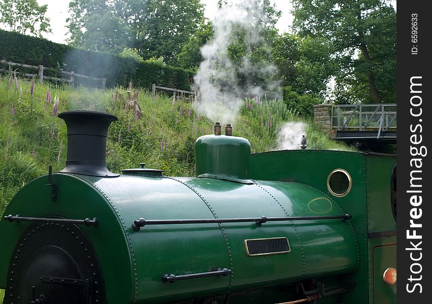 A green steam train  at a station