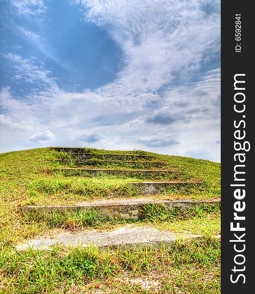 Flight of steps up a grassy slope in a cloudy sky