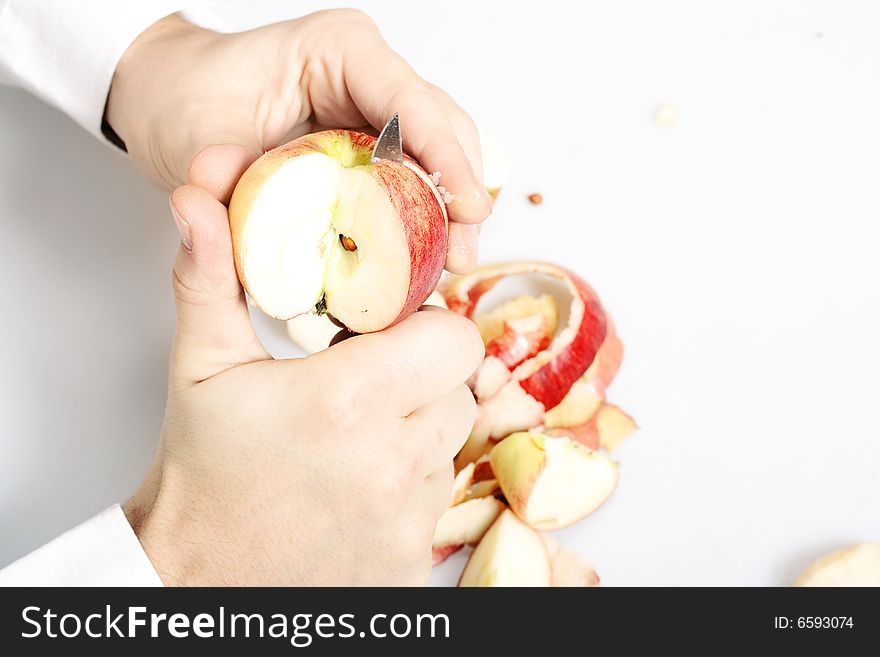 Apple cut by knife in hands.