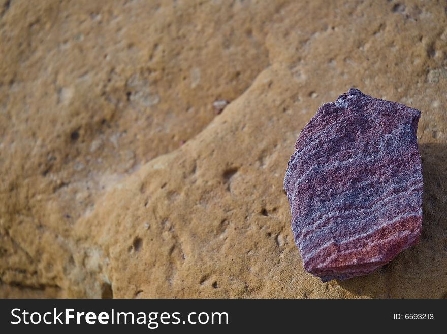 A purple rock on a brown rock. Found in Petra, Jordan.