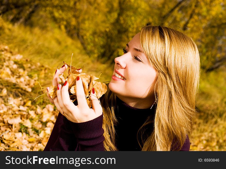 Pretty happy girl with yellow leaves in the park