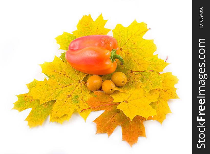 Yellow tasty plum and autumn leaves of maple with red sweet pepper on white background