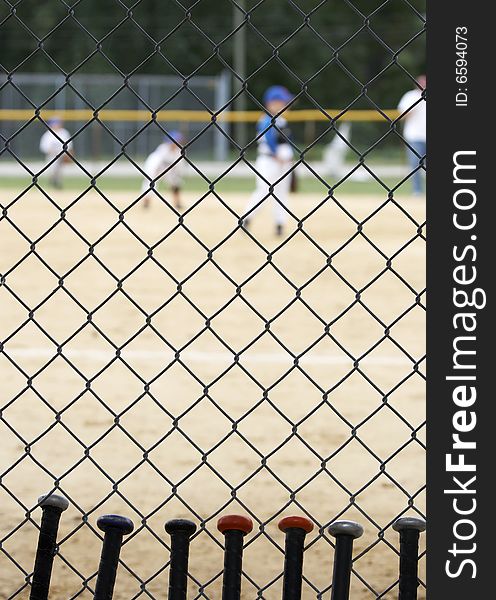 Baseball bats learning against dugout fence as game is played. Baseball bats learning against dugout fence as game is played