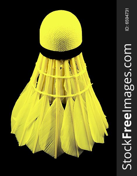 A yellow shuttlecock with feathers on the black background