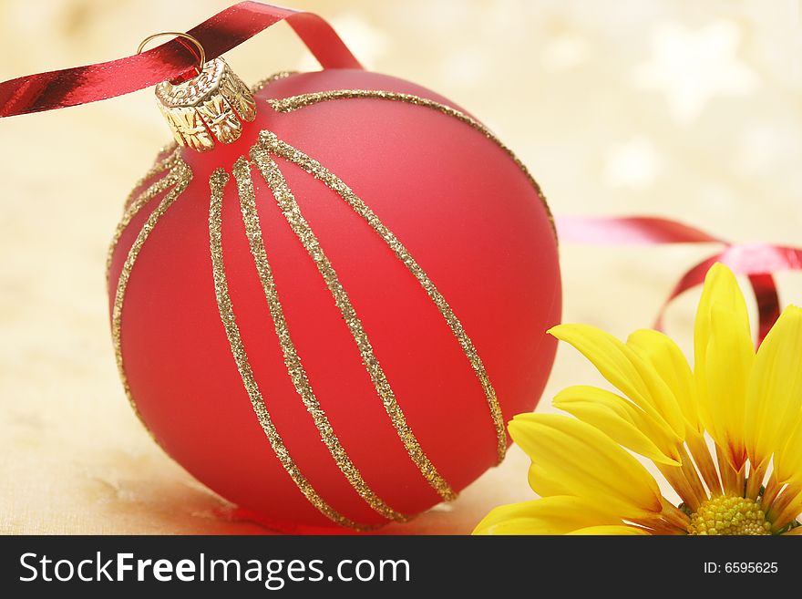 Christmas red ball with yellow flower on golden background.