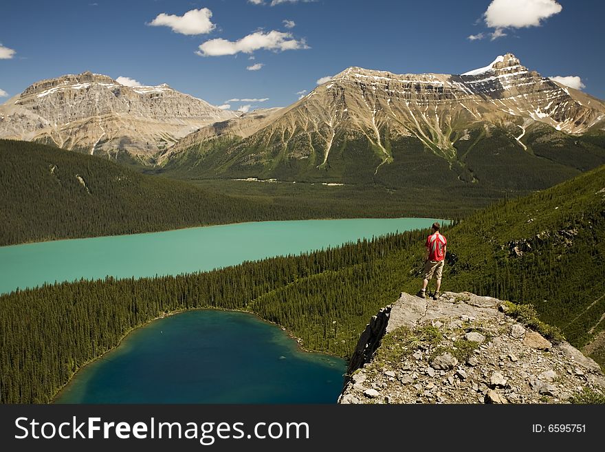 Young man standing on boulder above lakes