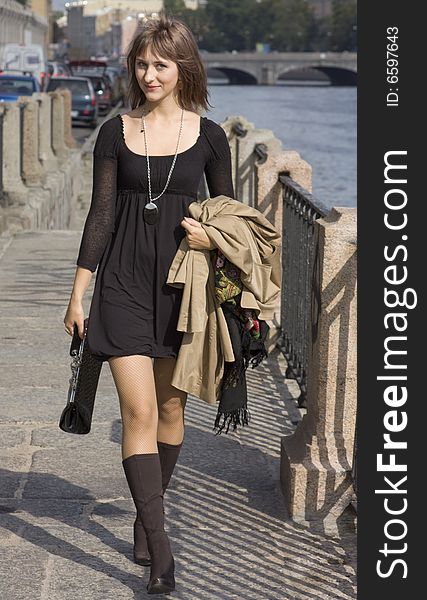 Beautiful young woman walking along an embankment