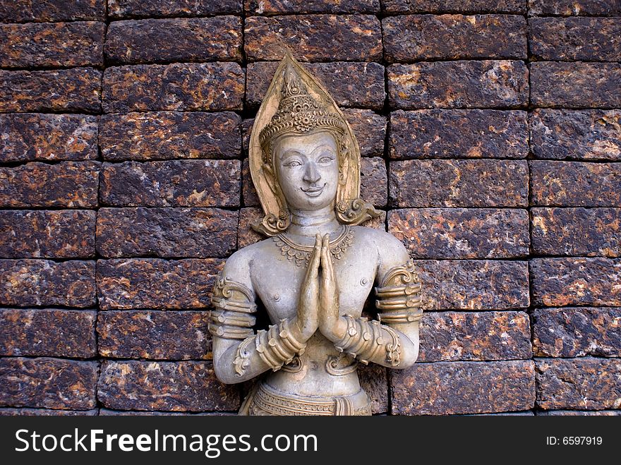 Golden praying budda on brick wall in thailand