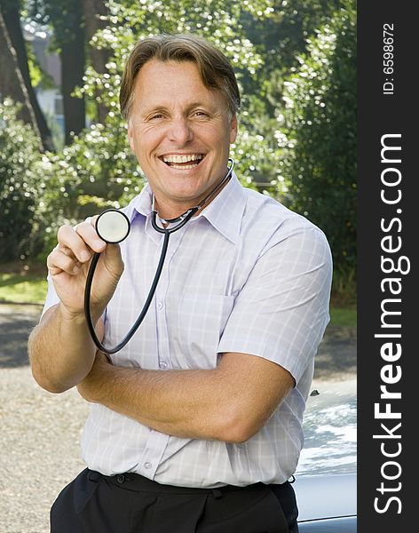 Handsome doctor in his forties is happy and smiling while holding his stethoscope out in a friendly manner. Handsome doctor in his forties is happy and smiling while holding his stethoscope out in a friendly manner