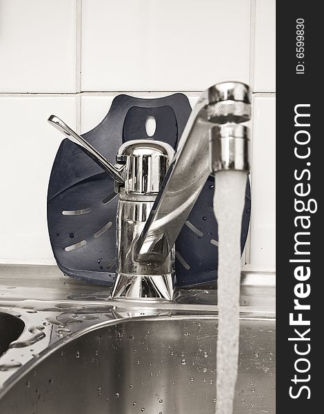 Chrome tap in the kitchen with flowing water