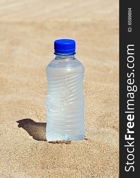 Plastic bottle with water on sand