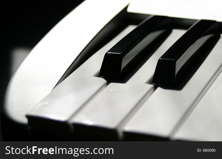 The white and black keys of a midi keyboard. Shallow depth with primary focus towards the top of the left black key. The white and black keys of a midi keyboard. Shallow depth with primary focus towards the top of the left black key.