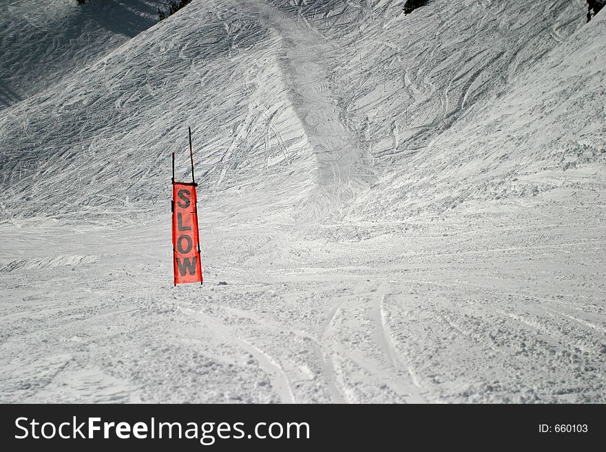 This is an orange sign you see on a ski slope. It is made of a see-through mesh material. Obviously used to caution skiiers to slow down. This is an orange sign you see on a ski slope. It is made of a see-through mesh material. Obviously used to caution skiiers to slow down.