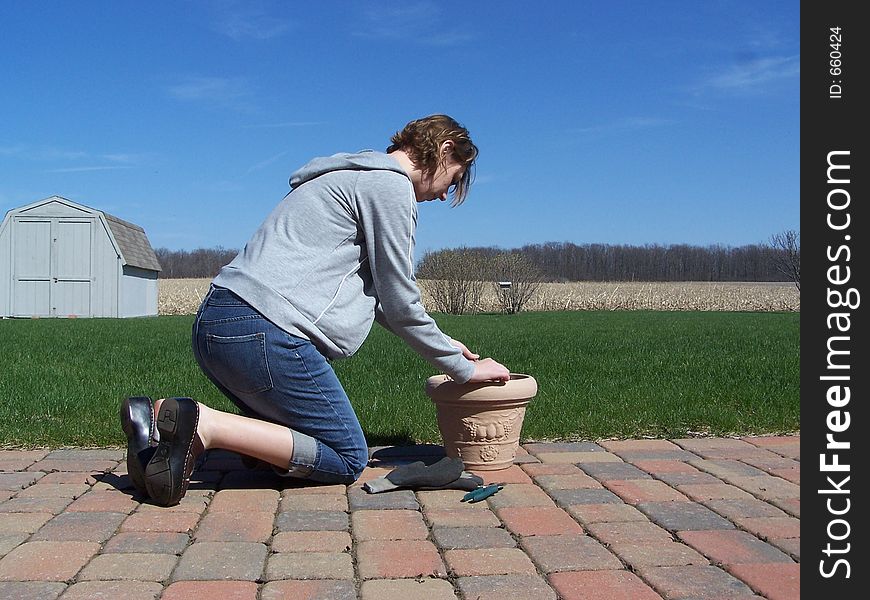 Photo of a woman preparing her potted plant for spring underneath a blue sky. Photo of a woman preparing her potted plant for spring underneath a blue sky.