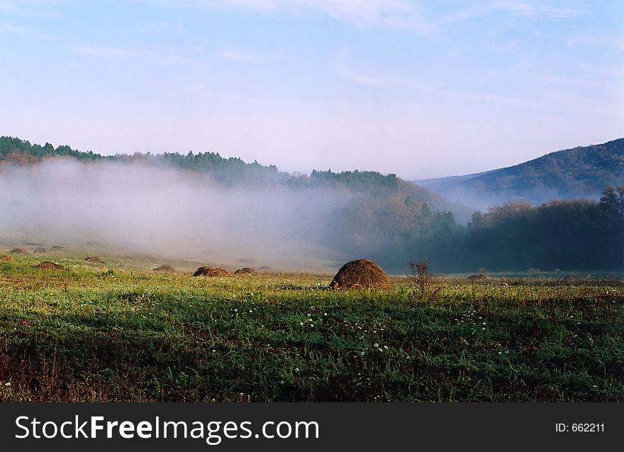 Meadow with stacks of hay in the fog in the morning. Meadow with stacks of hay in the fog in the morning