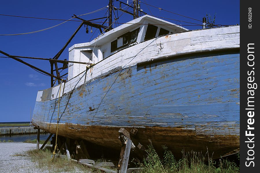 A damaged boat rotting away on the edge of the water.