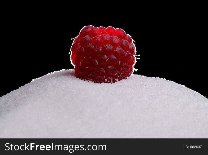 A raspberry atop a mound of sugar.