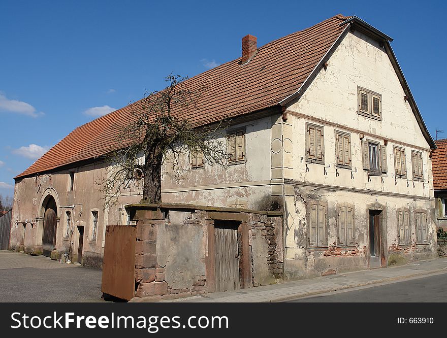 This old farmhouse of 1841 in the middle of a small German town has been boarded-up for some years now. The old tree is just beginning to have blossoms while the old farmhouse is rumored to be pulled down in the near future.