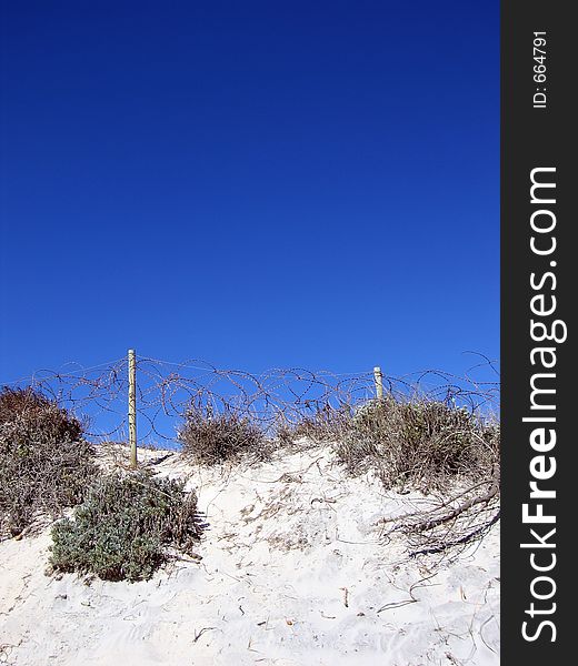Portrait shot of a coastal dune with barbed-wire fence. Portrait shot of a coastal dune with barbed-wire fence.