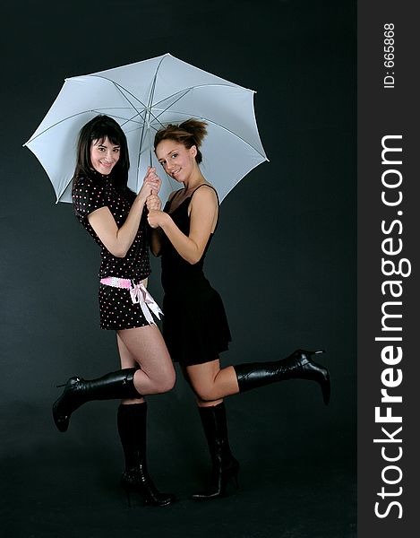 Two young beautiful women sharing an umbrella. Two young beautiful women sharing an umbrella.