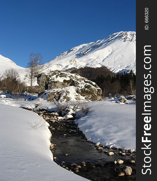 River on sunny snow glade. Caucasus, Russia. River on sunny snow glade. Caucasus, Russia