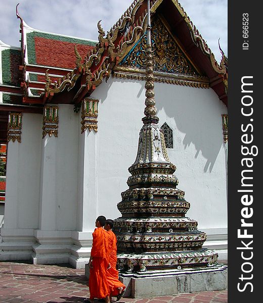 A Thai temple with two monks walking. A Thai temple with two monks walking