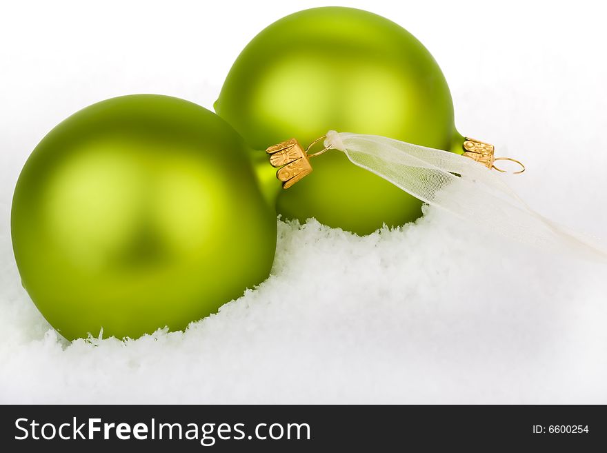 Go green this Christmas. Green Baubles on a bed of snow.