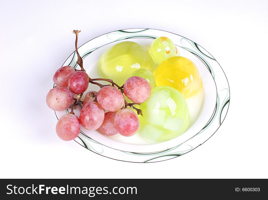 Jelly and a branch of grape in  dish on white  background. Jelly and a branch of grape in  dish on white  background