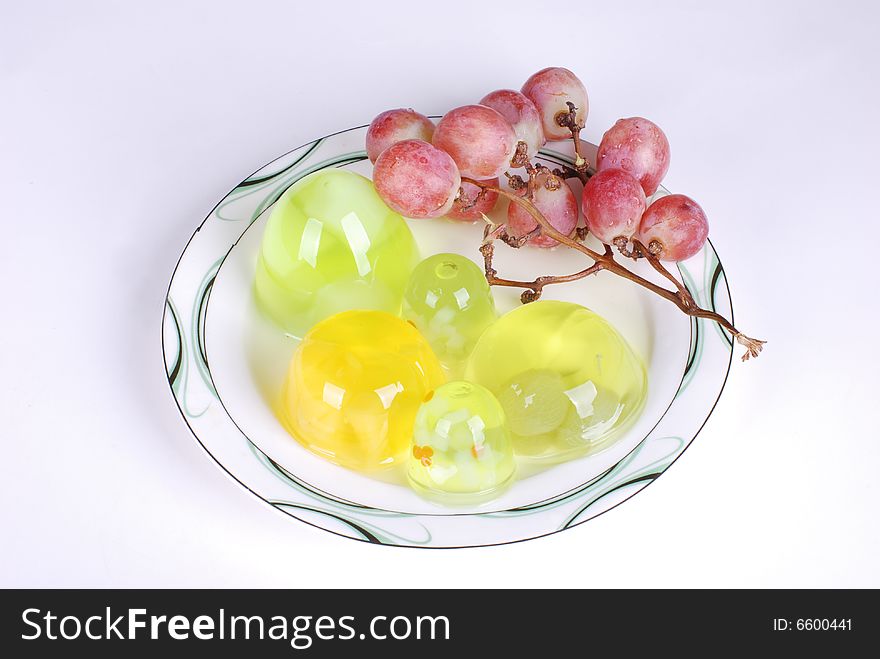 Jelly and a branch of grape in dish on white background. Jelly and a branch of grape in dish on white background