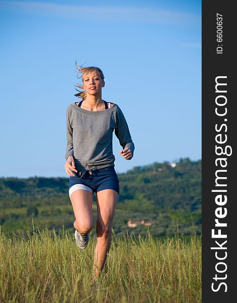 Sporty young woman jogging in a hilly meadow