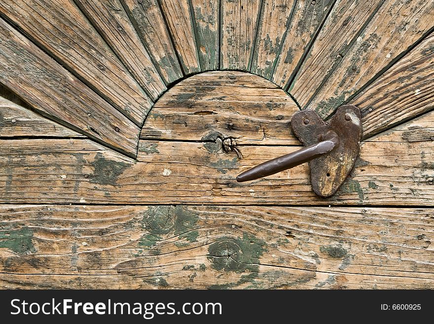 Detail of a door with a handle and sun ornament. Detail of a door with a handle and sun ornament