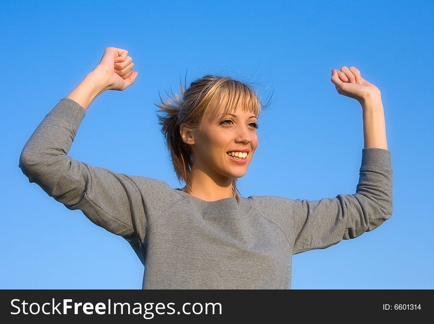 Young smiling woman spreading arms to blue sky. Young smiling woman spreading arms to blue sky