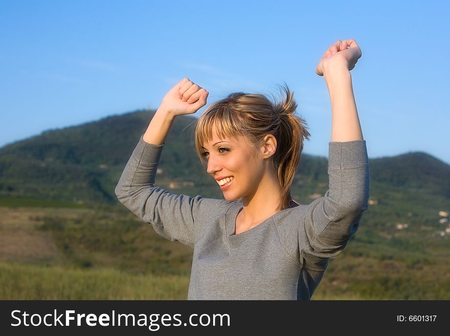 Young smiling woman spreading arms to blue sky. Young smiling woman spreading arms to blue sky