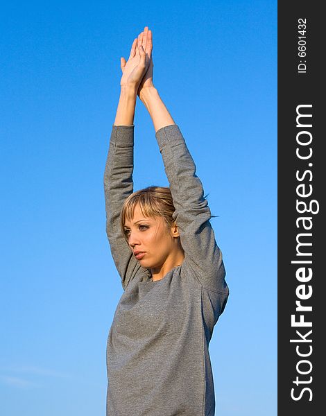 Young woman spreading arms to blue sky to stretching before exercising. Young woman spreading arms to blue sky to stretching before exercising