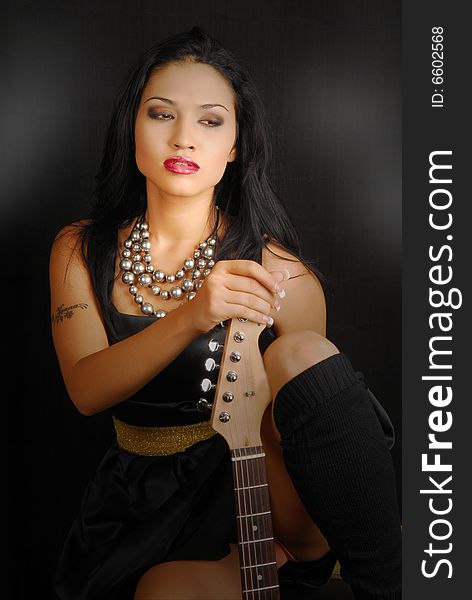 Attractive hispanic female rocker with guitar and dramatic lighting. Attractive hispanic female rocker with guitar and dramatic lighting