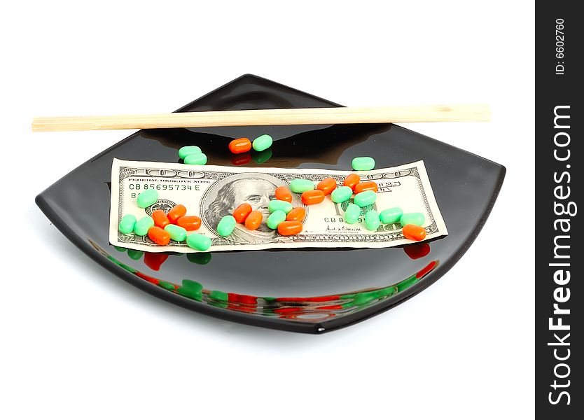 Expensive chemical diet - colored pills on black asian plate, 100 dollar note, and chopsticks