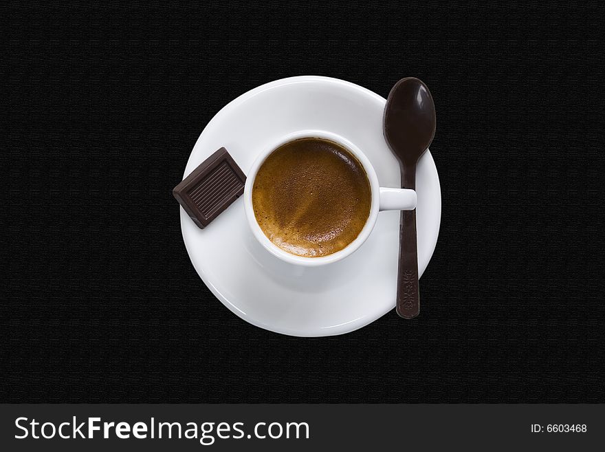 High angle view of a white cup of coffee with a piece of chocolate and a chocolate spoon. It has a clipping path. The background is a PS texture. High angle view of a white cup of coffee with a piece of chocolate and a chocolate spoon. It has a clipping path. The background is a PS texture.